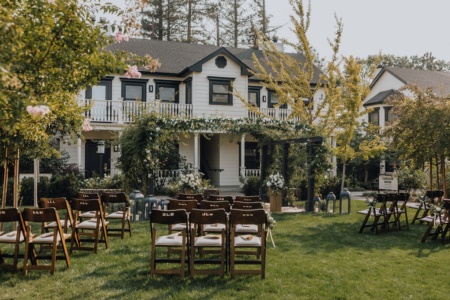 Charming wedding ceremony setting on lush west lawn of our historic property, with farmhouse cottages and rose bushes in background.
